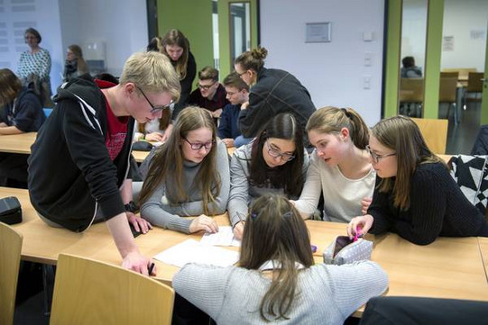 Schülerinnen und Schüler sitzen an einem Tisch