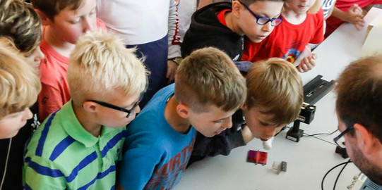 KinderUni im U Kinder im Grundschulalter schauen sich Versuchsanordnung an